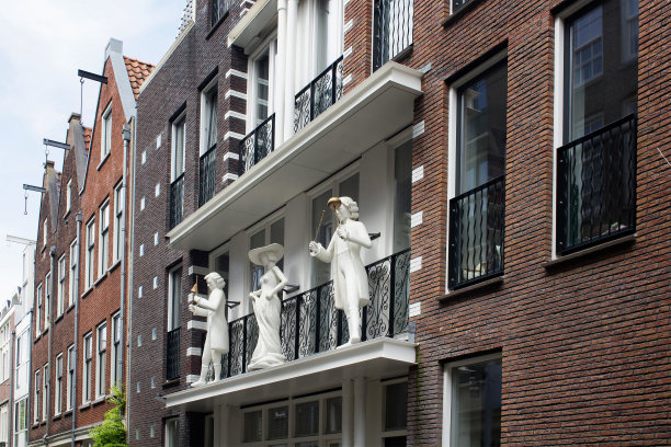 阿姆斯特丹的Jordaan社区的传统建筑阳台上的三个雕像。图片展示了荷兰的建筑风格和生活方式。图片下载