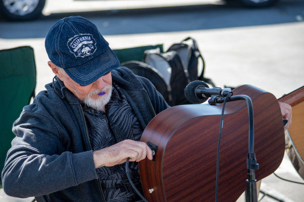 克里斯·哈根和迈克作为娱乐乐队在西米谷农家市场演奏吉他。在这张照片中，迈克把他的吉他插到扩音器上。图片下载