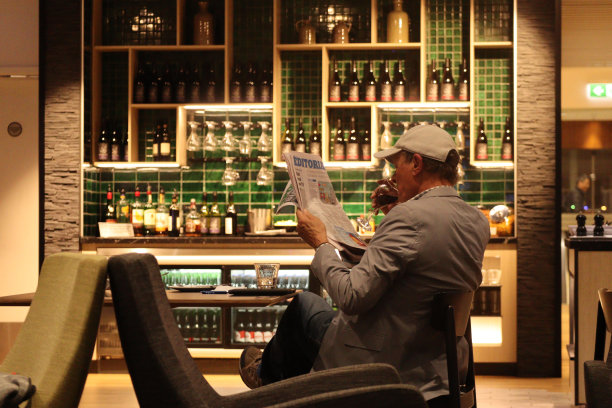 一名男子在机场候机室喝着葡萄酒等着飞机图片下载