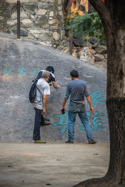 一个在巨石上画书法的人图片下载