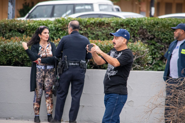 一名参与事故调查的司机在Balboa大道6750号前给自己的车拍了一张照片，一名洛杉矶警察和目击者在后面。图片下载