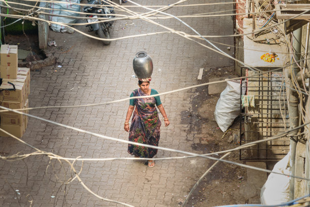 一名头上顶着大麻的印度妇女站在孟买达拉维贫民窟的街道上。印度图片下载