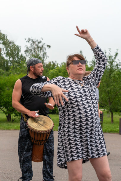 2019年6月30日，俄罗斯克拉斯诺亚尔斯克:一名戴眼镜的成年女性在公园里随着非洲Tam Tam鼓跳舞。党,垂直照片图片下载