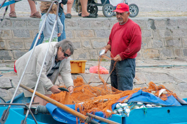 两个上了年纪的保加利亚渔民靠岸交易鱼。图片下载