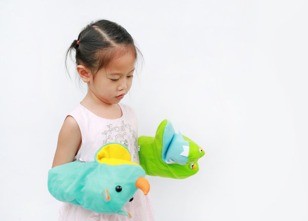 小亚洲女孩手玩动物木偶与她的母亲的手在白色的背景。教育的概念。图片下载