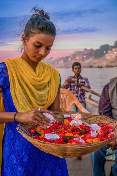 一个年轻的印度妇女准备宗教供品在划艇上的特写，将被放置在水为排灯节。图片下载