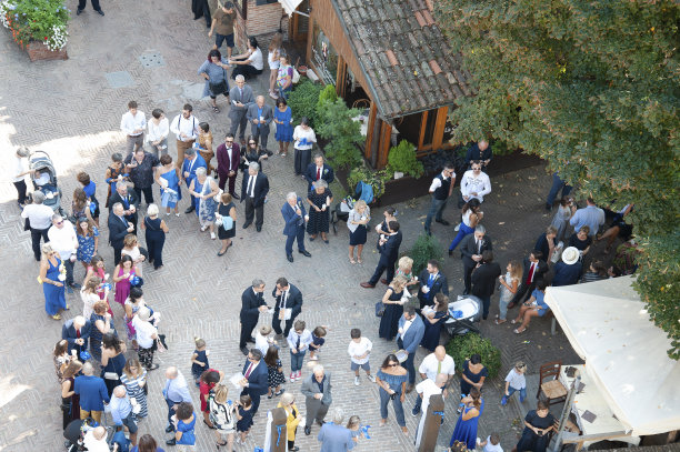 一大群穿着考究的人在绿色住宅区的村庄街道上社交。前视图。图片下载