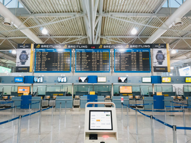 雅典国际机场主航站楼空旷的出发大厅、空无一人的值机柜台和百年灵腕表广告的出发显示屏图片下载