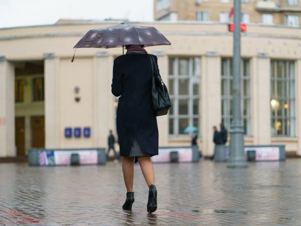 女人撑着雨伞匆匆赶往地铁入口图片下载