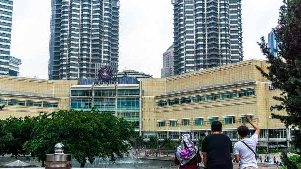 当地游客的后视图与Suria KLCC大楼和马来西亚国家石油公司的双子塔作为背景在白天。图片下载