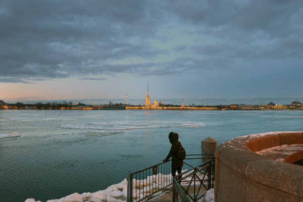 一个穿着夹克背着背包的女人看着涅瓦河图片下载