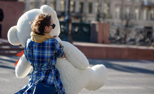 2020年5月30日，俄罗斯圣彼得堡:一个快乐的女孩在城市的街道上拿着一个巨大的泰迪熊玩具图片下载