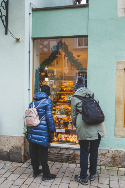 在德国陶伯河河畔的罗滕堡，人们看着装饰得灯火辉煌的商店橱窗图片下载