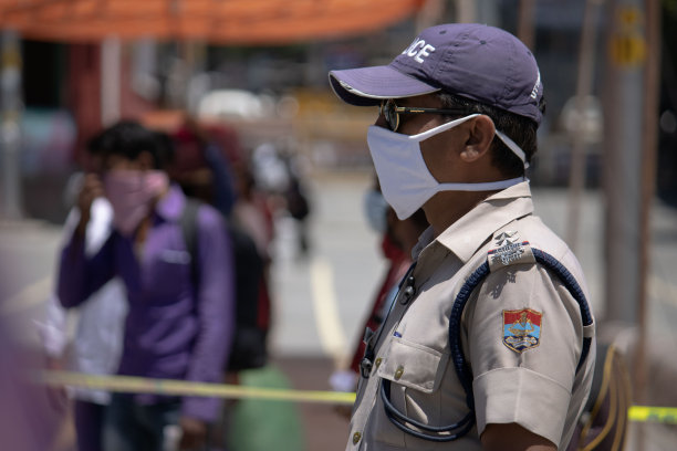 警察在工作，人们因为冠状病毒大流行戴口罩。图片下载