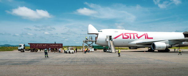 一架高装载机从一架波音B747巨型喷气式飞机上卸下装在木箱里的牲畜，该飞机有一个大开的前鼻货舱门，然后转移到一架牲畜运输船上图片下载