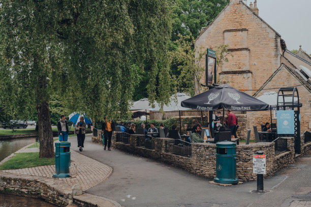在英国科茨沃尔德波顿河畔的Greene King酒吧，人们在Old Manse酒店的户外桌子旁。图片下载