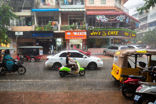柬埔寨雨季的公寓楼图片。街道满是水，交通在商场前面。图片下载