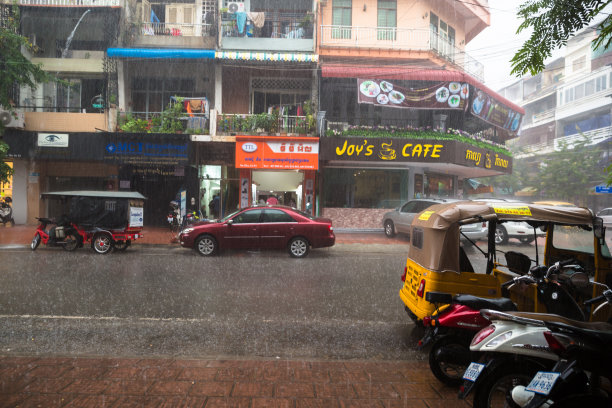 柬埔寨雨季的公寓楼图片。街道满是水，交通在商场前面。图片下载
