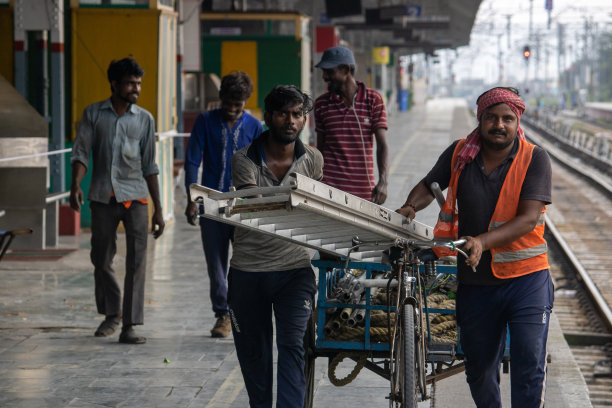 在火车站月台用人力车拉楼梯的工人，在冠状病毒流行中。在火车站站台上用人力车拉楼梯图片下载