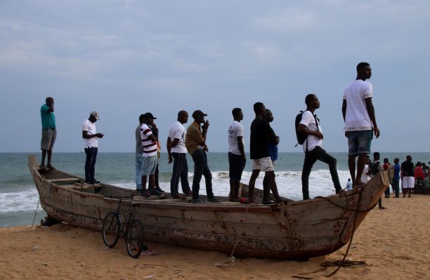 在西非多哥Lomé的公共海滩上，人们站在渔船上。图片下载