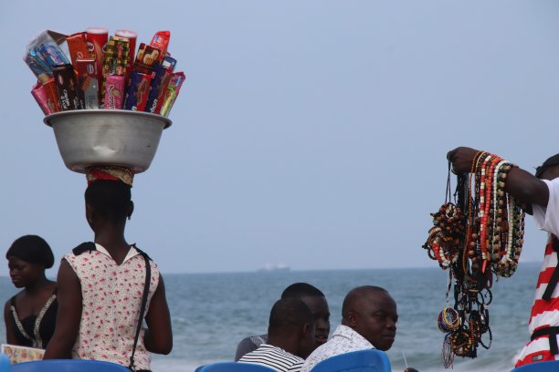 在西非多哥Lomé的海滩上，一名妇女头上顶着包装好的饼干。图片下载