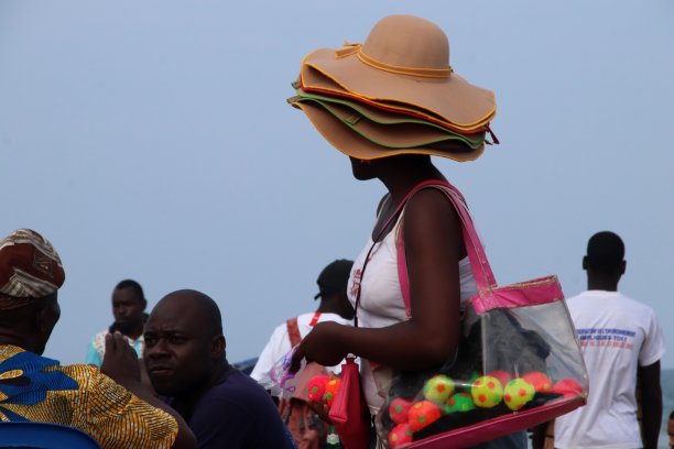 在西非多哥Lomé的海滩上，一名妇女头上戴着各种各样的帽子。图片下载