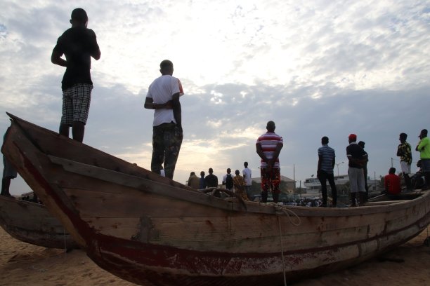 在西非多哥Lomé的公共海滩上，人们站在渔船上。图片下载