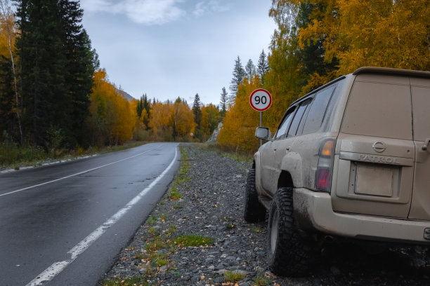 越野越野车在秋天的乡村道路与速度标志前危险转弯。图片下载