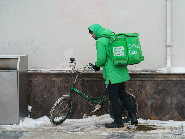 大雪纷飞的冬天，送快递的人骑着自行车图片下载