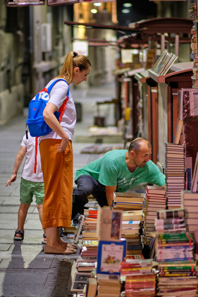 塞尔维亚贝尔格莱德，一位年轻的妈妈带着孩子在街边买书图片下载