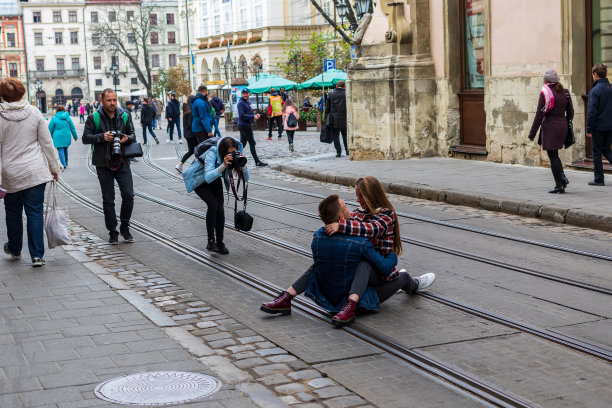 一组摄影师在老城的古老街道上拍摄了一名浪漫的青年男子和一名年轻女子拥抱亲吻的照片。图片下载