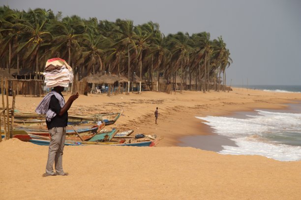 西非多哥阿韦波佐海滩上，一名海滩小贩头上顶着织物。图片下载
