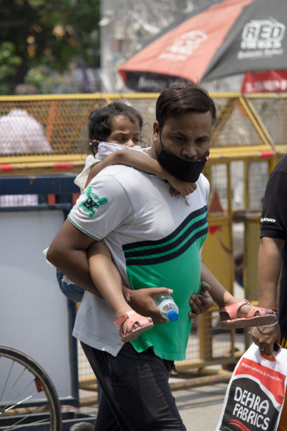 男人们背着他的孩子，戴着面具。图片下载