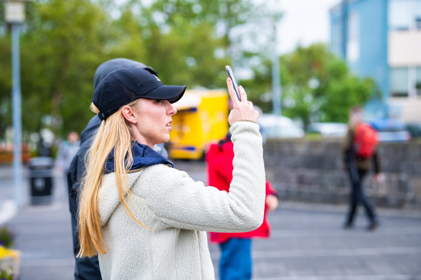 在市中心街道上，一名年轻的白人女性用手机拍摄路德教会教堂的侧面照片图片下载
