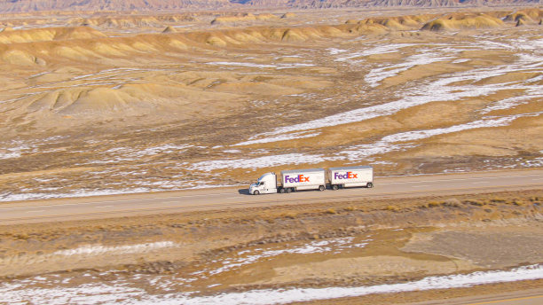 空中图片:在阳光明媚的冬日里，联邦快递卡车在冰雪覆盖的犹他州沙漠上运送货物图片下载