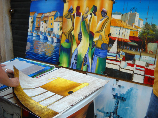 杜布罗夫尼克，克罗地亚，2010年8月5日人们购买街头艺术家的作品。出售纪念品及创意作品。人的手移动和触摸彩色的图画。亚得里亚海海岸的旅游景点。图片下载