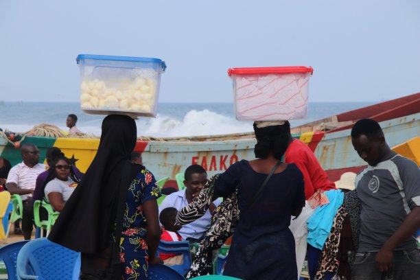 女海滩小贩头上顶着牛奶袋，Lomé，多哥，西非。图片下载