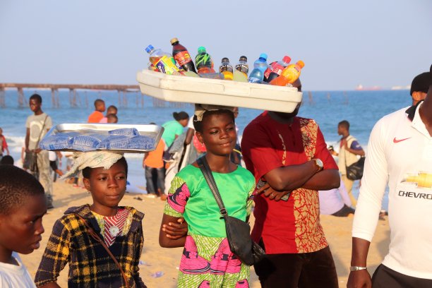 在西非多哥Lomé的海滩上，一名年轻女子头上顶着饮料。图片下载