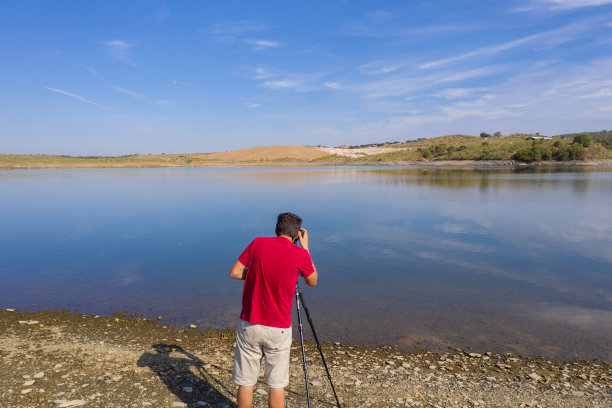 在葡萄牙阿连特霍，一名白人男子用无人机拍摄一个湖泊和倒影的风景图片下载