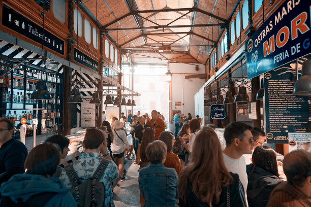 在马德里市中心的圣米格尔市场，人群和游客。令人惊叹的建筑和美丽的食物。老风格的图像在背光与太阳耀斑。图片下载