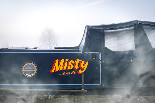 朦胧的江船画着写着的文字，可见薄雾从运河边冉冉升起的蓝窄船回家图片下载