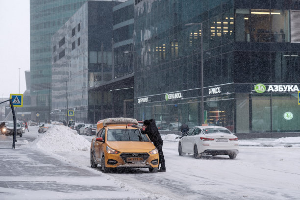 一名出租车司机擦拭挡风玻璃和雨刷上的冰和雪。图片下载