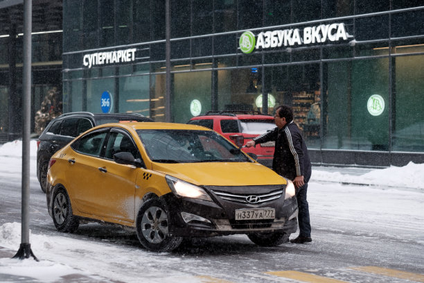 一名出租车司机擦拭挡风玻璃和雨刷上的冰和雪。图片下载