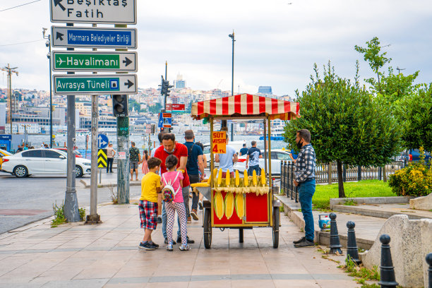 伊斯坦布尔夏天的大街上，一名男子在推车上卖烤玉米。土耳其街头小吃生意图片下载