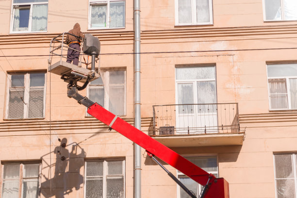一个工人在升降平台上清洗房子的正面图片下载