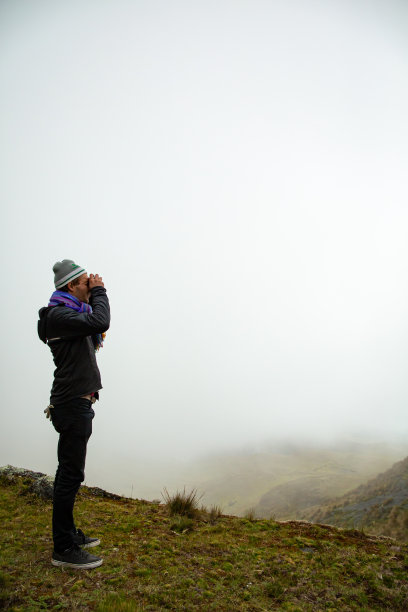 一名身穿黑色衣服的白人男子在一个背景中有很多雾的山顶上拍了一张照片图片下载