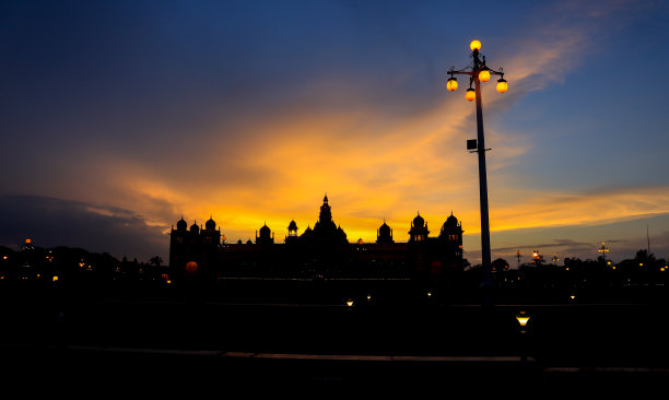 这是黄金时间拍摄的著名地标安巴维拉皇宫的剪影照片，在印度迈苏尔迷人的橙色和蓝色天空下。图片下载