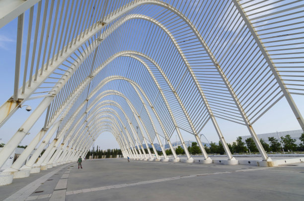 在夏季阳光明媚的日子里，人们在由西班牙著名建筑师圣地亚哥·卡拉特拉瓦设计的现代雅典奥林匹克体育中心内散步、骑自行车和玩耍图片下载