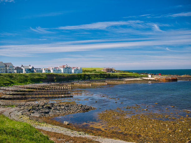 英国北爱尔兰安特里姆堤道海岸Portballintrae海湾的防波堤护坡在退潮时伸入大海。这张照片拍摄于一个阳光明媚的夏日。图片下载