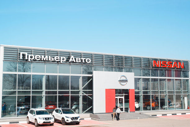 外面是日本汽车制造商日产汽车的展示厅。建筑立面，停车场和招牌上的标志在清晰的蓝天背景。俄罗斯斯摩棱斯克04.18.2021图片下载